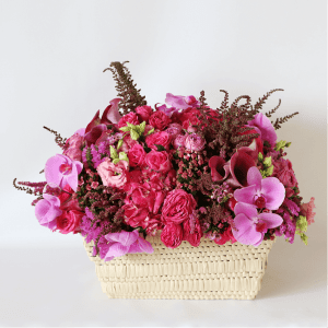 pink arrangement with phalaenopsis orchids, pink spray rose, pink astilbe, pink statice, pink calla lily, arranged in a basket