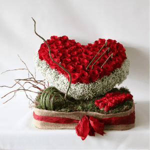 heart shaped red roses with gypsophelia on a bed of moss and red ribbon