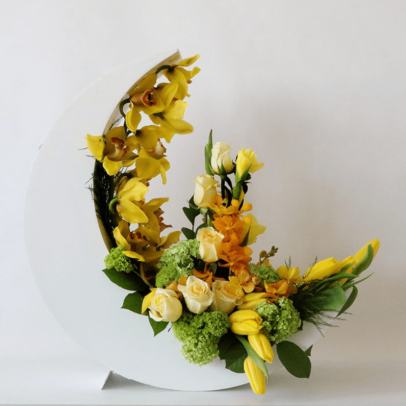 Yellow tulips, cymbidiums, orchids arranged in a white crescent moon