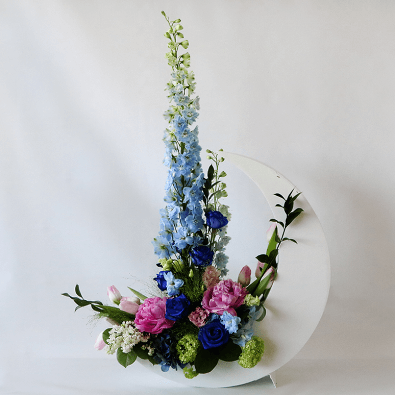 blue delphinium and pink peonies in a white crescent moon