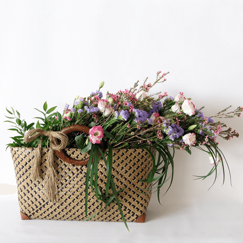 Natural looking flowers eustoma, wax flower, statice and greenery in a basket