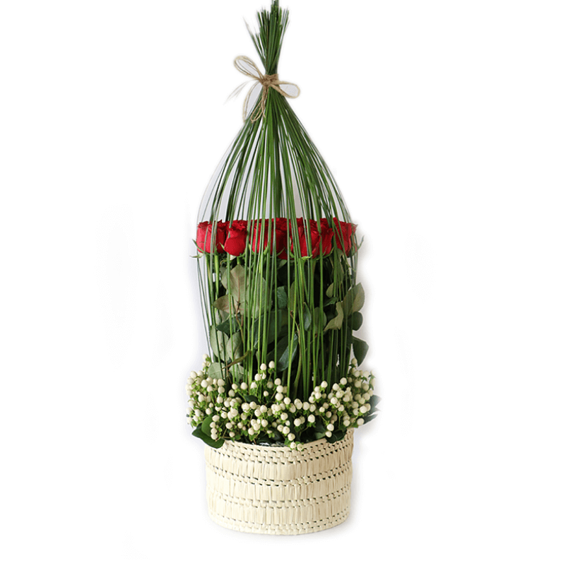 red roses surrounded by bear grass and hypericum arranged in a basket