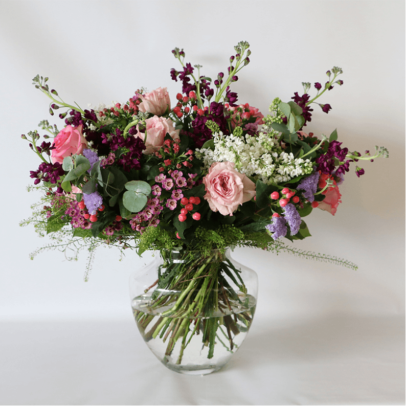pink, purple white and green flowers arranged in a glass vase