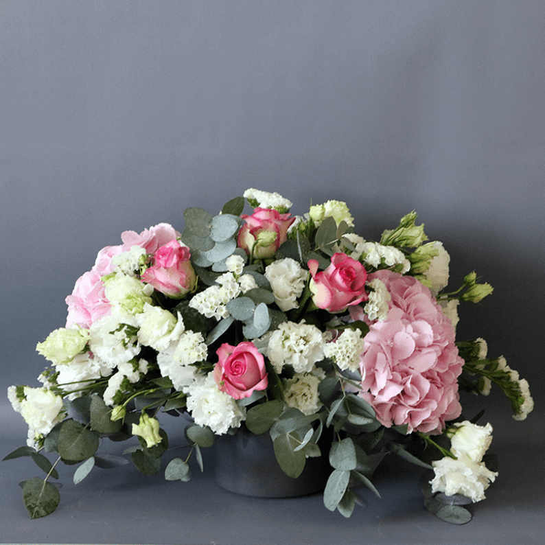 pink roses, pink hydrangea, white statice and eustoma arranged in a ceramic vase