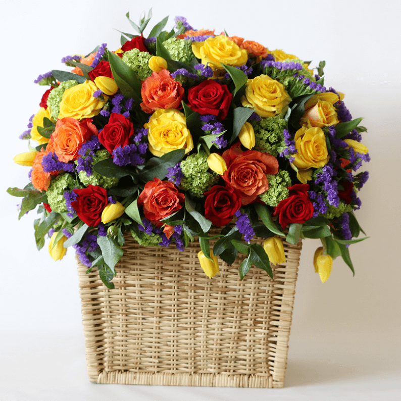 orange, yellow, red roses, with yellow tulips, purple statice in a basket