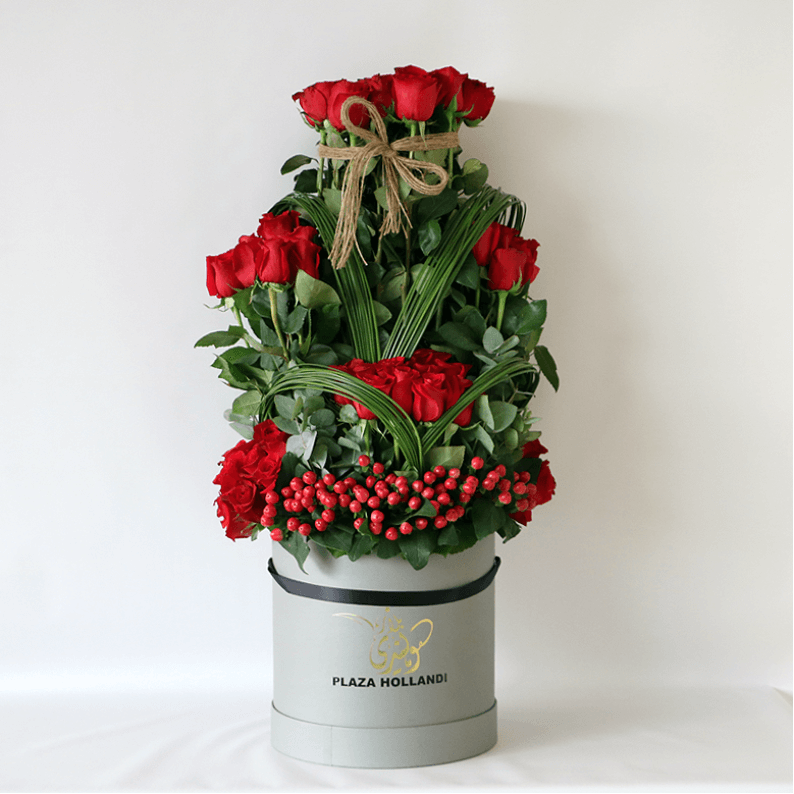 red roses, hypericum and greenery in a plaza hollandi hat box