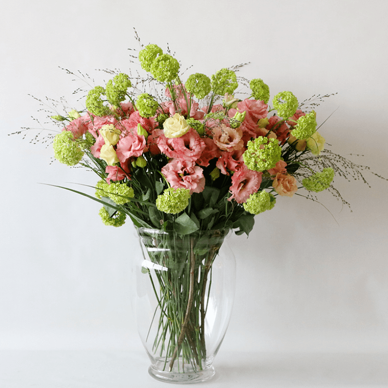 Pink eustoma in a glass vase with snowball and grass