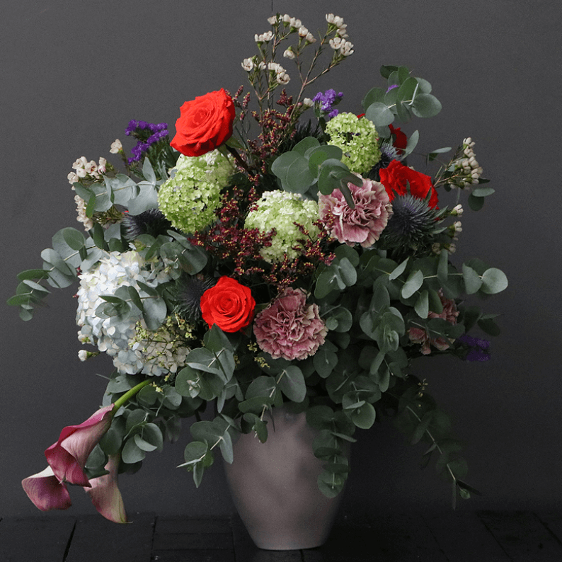 large natural floral design with red roses, carnations, snowball, wax flower and eucalyptus
