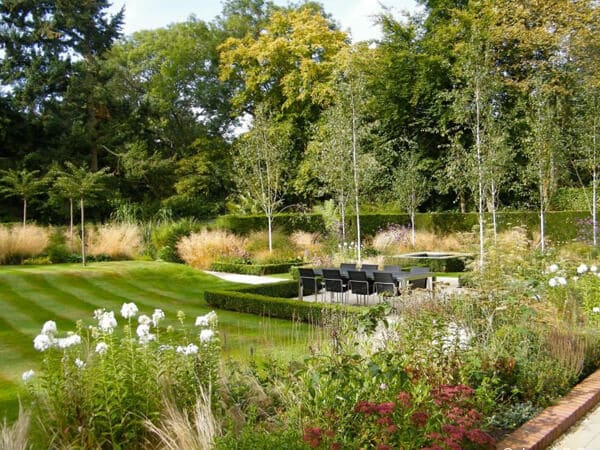 Classic garden design with beach trees, grasses and dining area