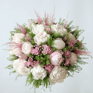 Pink and white peonies with bouvadia in a bouquet with pampas grass