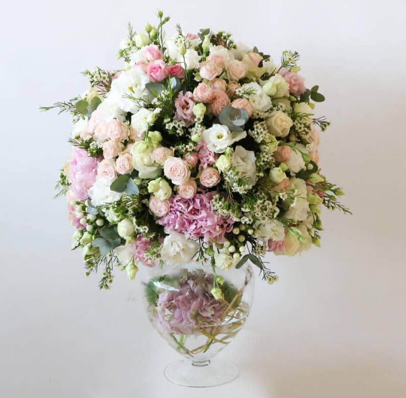 Pink, peach, white and green round flower arrangement on a glass vase