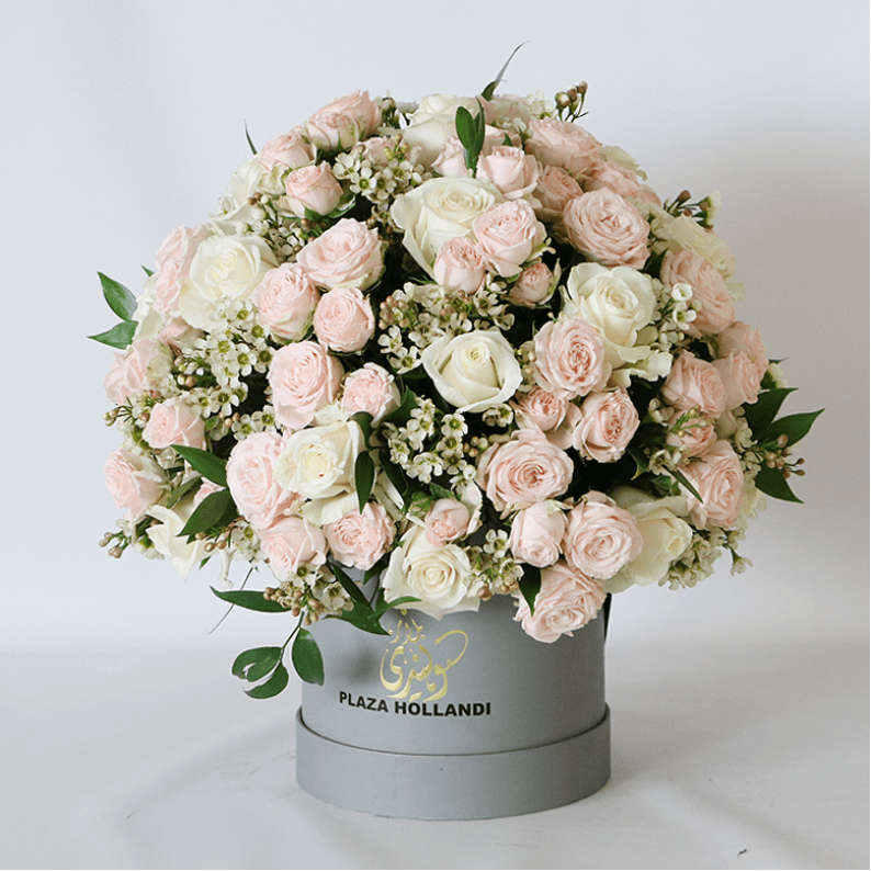 peach and pink spray roses in a round design in a hat box