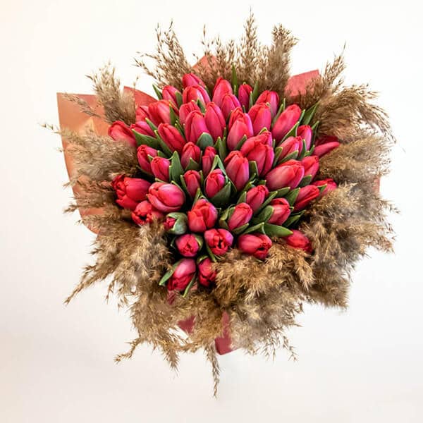 Red tulips with pampas grass wrapped in paper