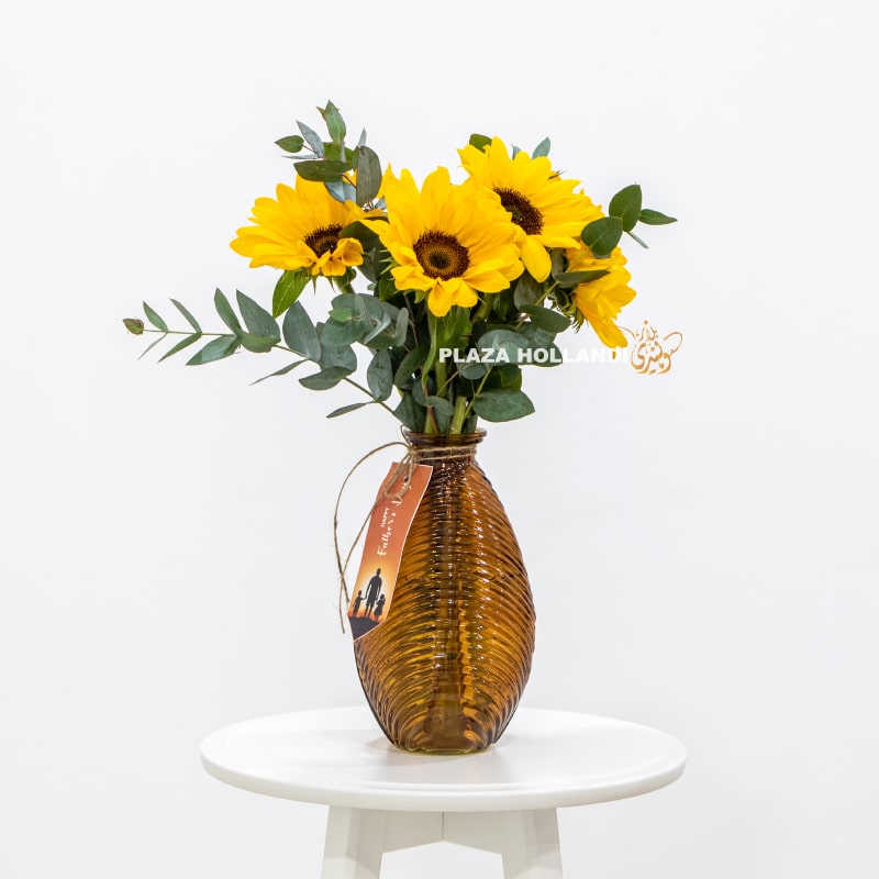 Bouquet of sunflowers in a brown vase with a fathers day card