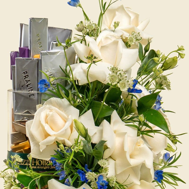 White roses and blue delphinium bouquet with chocolates